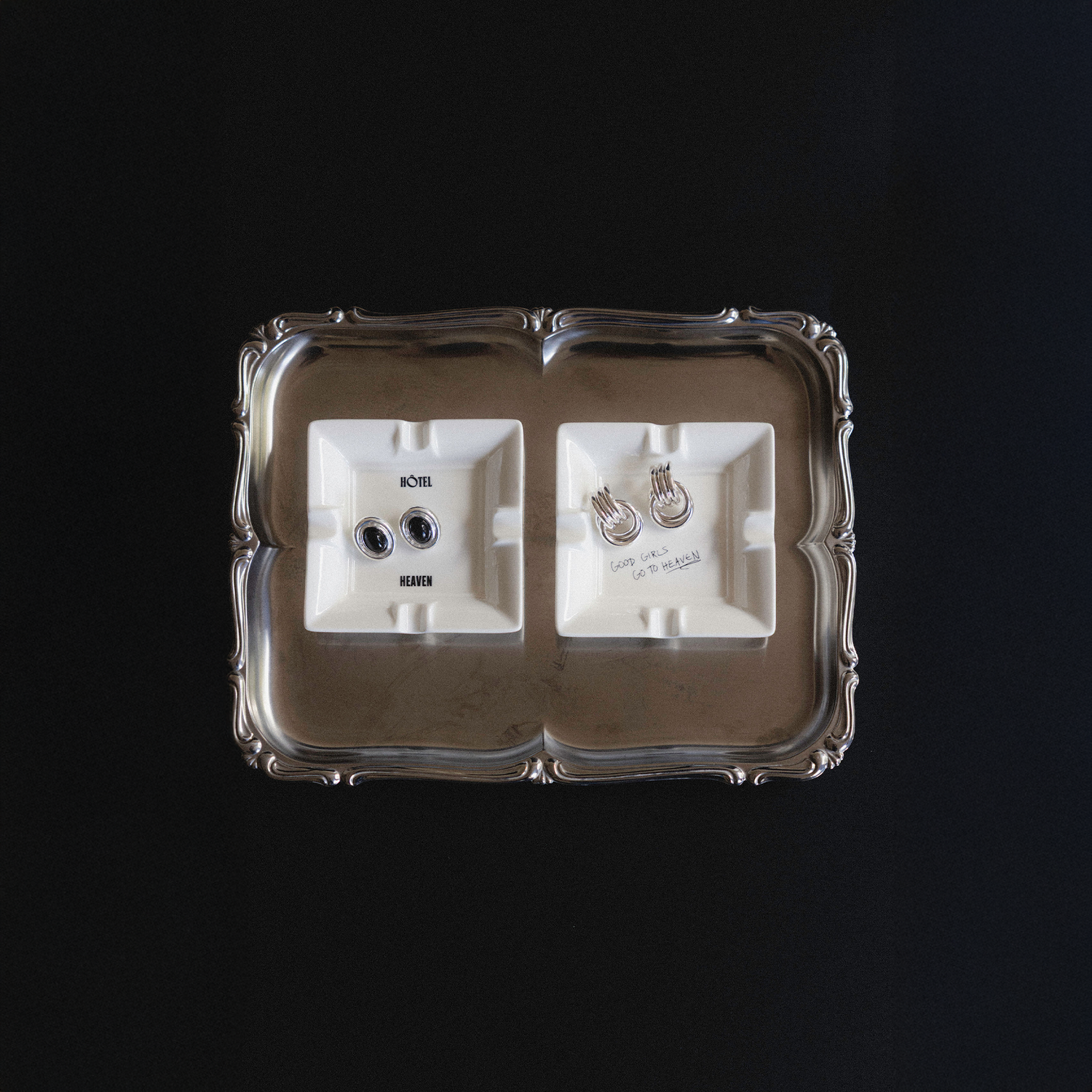Silver tray with two white mini ashtrays that read: Hotel Heaven and Good Girls Go To Heaven, respectively. 