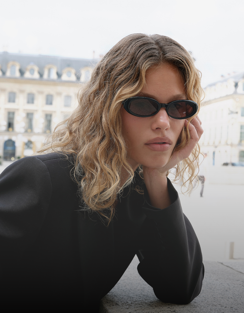 Person wearing sunglasses with a blurred building in the background